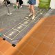Player playing classic hopscotch at One Punggol, Singapore, hopping across the squares with one foot
