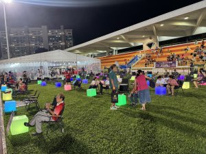 Guests enjoying an outdoor festival seated kermit chairs with glowing LED cubes tables