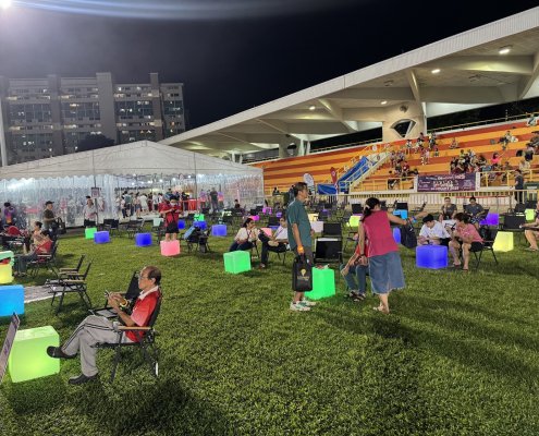 Guests enjoying an outdoor festival seated kermit chairs with glowing LED cubes tables