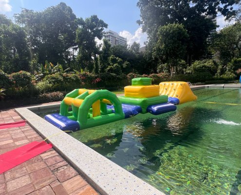 Brightly colored inflatable Bridge with a green base and yellow arch, floating on water.