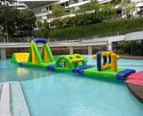 Water obstacle shaped like a bridge with an arched frame and openings, part of an inflatable course.