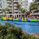 Participants navigate the crawl section, ducking under bright yellow square-shaped inflatables on a floating platform.