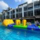 Participants crawl under square yellow inflatable arches on a water obstacle course at Belgravia Villas, Singapore