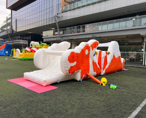 Vintage Dragon Playground inflatable at Tanglin Trust School in Singapore, designed with a white body and bright orange dragon-shaped features.