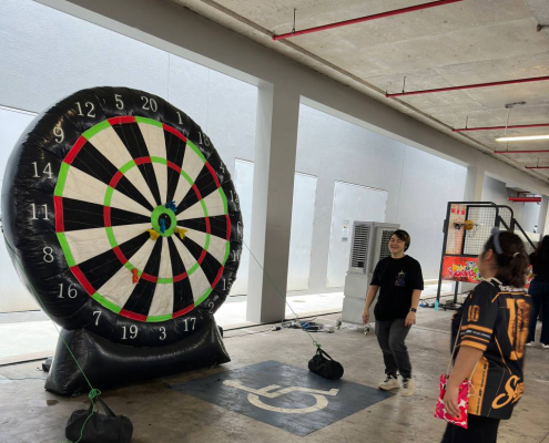Large inflatable dart game at Green Forest Park in Singapore, with participants aiming suction darts at an oversized dartboard target.