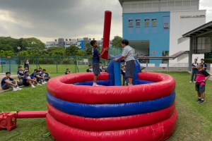 Two people playing on the Gladiator Dome inflatable game at Canberra Sec School event in Singapore, trying to knock each other off the platforms