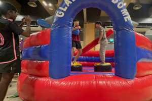 Players competing inside the Gladiator Dome inflatable at Lower Kent Ridge Rd in Singapore, balancing and trying to stay on their platform.