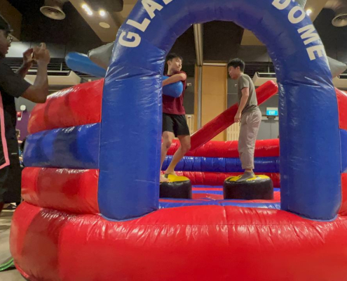 Players competing inside the Gladiator Dome inflatable at Lower Kent Ridge Rd in Singapore, balancing and trying to stay on their platform.