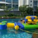 Kids maneuvering through the Grill obstacle on a floating water course, dodging soft barriers.