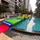 The Hill inflatable obstacle with a green climbing slope and blue handles, part of a floating water course.