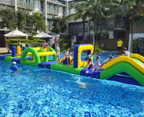 Children climbing up the Hill using blue handles before sliding down the opposite side into the water.