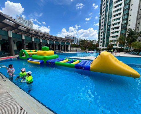 A floating inflatable challenge called the Hurdle, with long green side supports and three narrow crossing poles.
