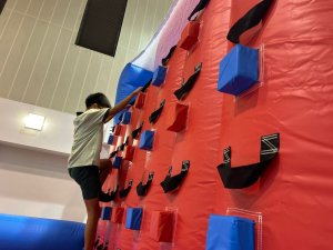 Children climbing a red inflatable rock wall inside the indoor sports hall of Farrer Park Primary School, Singapore.