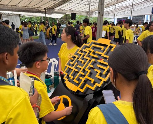 Students playing Maze Runner at Anderson Secondary School, Singapore, focusing on moving the maze board with precision.