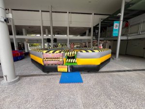 Close-up of the Meltdown inflatable game at Singapore Polytechnic showing its circular inflatable base and bright green rotating arm.