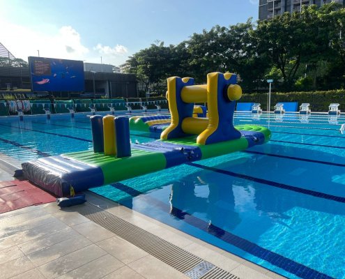 Inflatable water obstacle featuring three vertical pillars designed for participants to walk or step through.