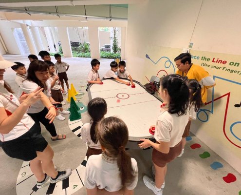 Students laughing and enjoying a regular air hockey game at Henry Park Primary School, Singapore.