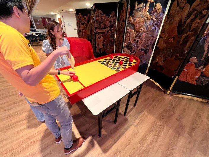 People concentrating while rolling a ball down the track in a Roll a Ball game at The Singapore Buddhist Lodge.