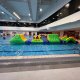 Inflatable water obstacle with a yellow slope, where participants climb up using blue handles and slide down the other side.