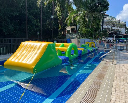 Slope inflatable obstacle featuring a yellow incline with green sides and blue handles for climbing.