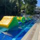 Slope inflatable obstacle featuring a yellow incline with green sides and blue handles for climbing.