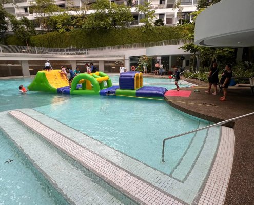 The Slope obstacle on a water course, designed with bright yellow and green colors and a built-in slide.