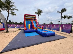 Inflatable Sports Climb game at Siloso Beach Walk, Singapore, showing a vibrant structure with wall climbing, a side slide, and three upright inflatable pillars before the wall.