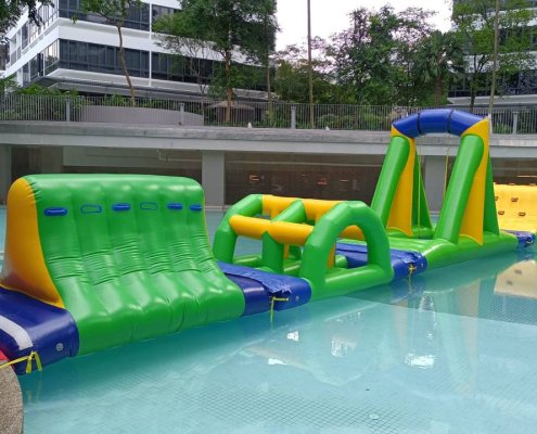 Inflatable water obstacle with a central rope suspended from a triangular green support, designed for swinging from one platform to another.