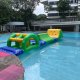 A green inflatable arch with a yellow horizontal bar crossing the center, part of a water obstacle course.