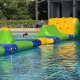 Players navigate The Bar, a green arch with a yellow bar, in a water inflatable course, testing balance and agility.