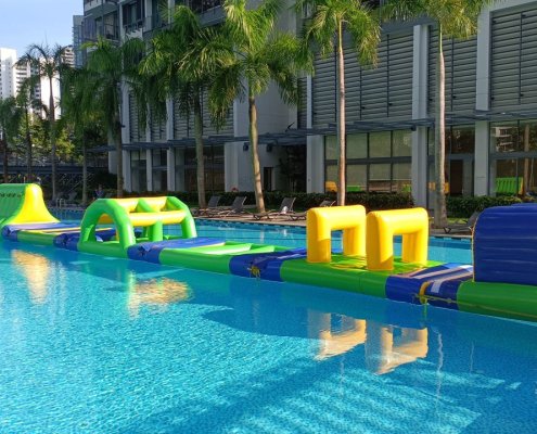 A green inflatable water obstacle with a V-shaped open path in the center, designed for players to walk along narrow sides.