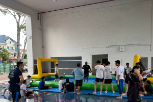 Water Soccer- Regent Secondary School 1 Excited students at Regent Secondary School chasing the ball in a fun-filled water soccer game, surrounded by splashes and bright inflatable walls in blue and yellow, Singapore.