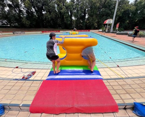 Players crossing through the i-Beam inflatable, carefully balancing as they walk through the open center arch.