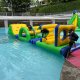 Participants crawling through the arch of the i-Beam obstacle on a water course, surrounded by splashes and laughter.