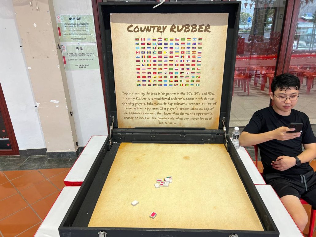 A collection of small rectangular rubber erasers, each printed with different country flags, arranged on the ground for a nostalgic old-school game popular in Singapore.