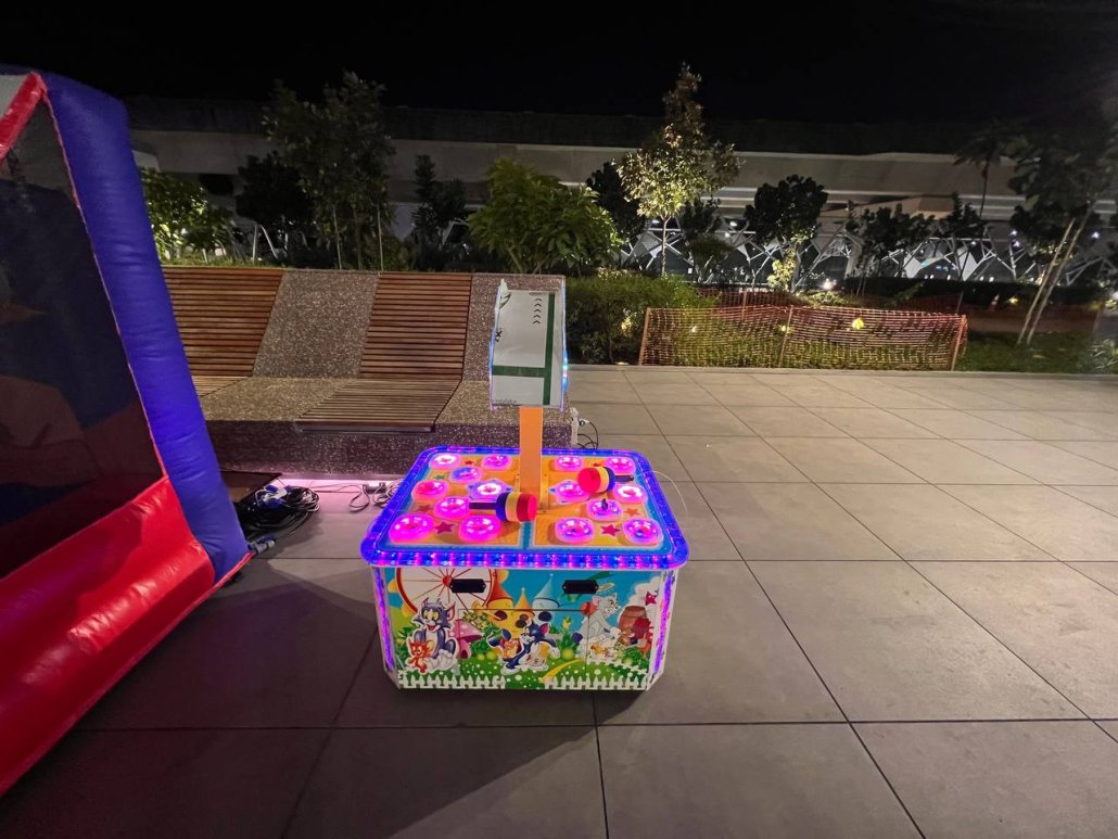 Duo Whack a Mole - One Punggol Brightly lit Duo Whack-a-Mole arcade game at One Punggol, Singapore, with double sets of hammers and popping moles.