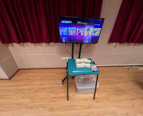 A Kinect gaming setup with a motion-sensing camera placed below a TV screen displaying a dance game, ready for hands-free play at Bedok South Secondary School, Singapore.