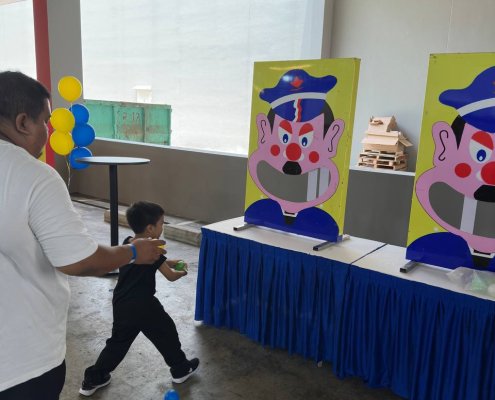 A player mid-throw aiming a soft ball at the toothy grin of the character, ready to knock a tooth off at Green Forest Park, Singapore.