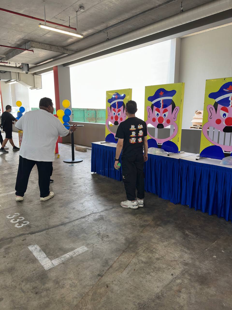 Participant aiming a soft ball at the cartoon character's teeth with focus and excitement, ready to knock the tooth off — captured during a lively moment at Green Forest Park, Singapore.