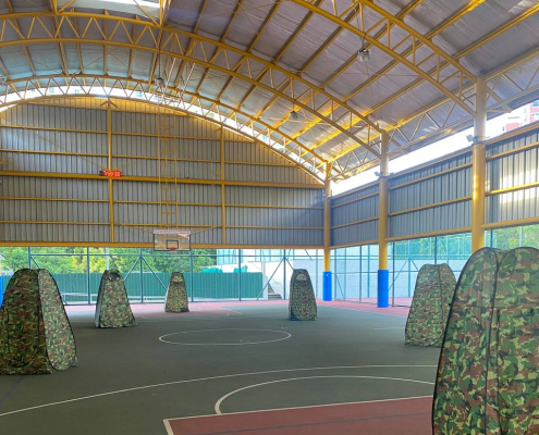A group of medium-sized laser tag tents with camouflage patterns, arranged side by side and ready for gameplay at Tampines Meridien Junior College, Singapore.