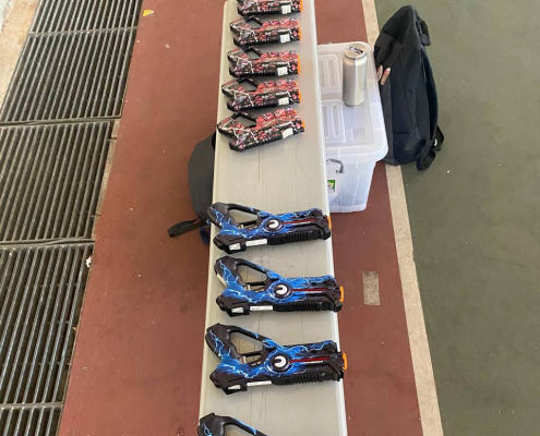 Multiple laser tag guns in bright blue and red colors neatly displayed on a table, prepared for players at Tampines Meridian Junior College, Singapore.