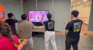Four people playing Just Dance on a Nintendo Switch station with TV at an event.