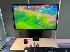 Close-up of Nintendo Switch console connected to a large screen TV on a game station.