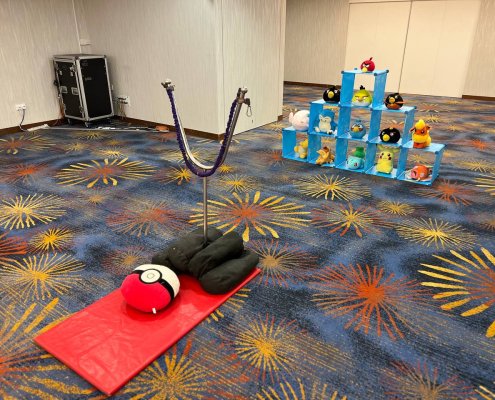 Pokémon Catch game setup at OCC Singapore featuring a slingshot-style challenge with Poké Balls and plush dolls