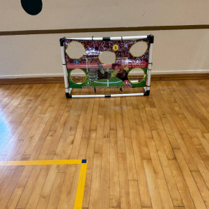 A soccer-themed challenge with a goal covered by a banner with five circular cutouts, designed for players to test their aim and accuracy at Gongshang Primary School.