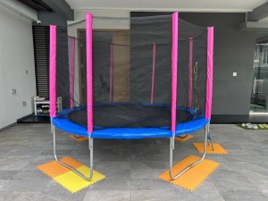 A clean, fully assembled trampoline with blue or pink padding standing in an indoor space, ready for rent at Jalan Khairuddin, Singapore.