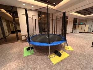 A trampoline in bright blue colors featuring strong safety poles and netting, ready for fun at The American Club, Singapore.