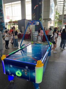 Kids playing LED air hockey at an indoor arcade game station