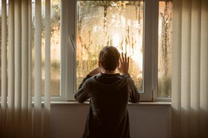 Child looking out the window at rainy weather during an indoor event