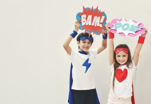 Boy and girl in superhero costumes at hero themed birthday party celebration